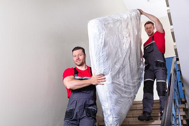 two people carrying a box spring down a staircase in El Dorado Hills